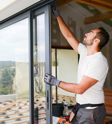 handsome young man installing bay window in a new house construction site handsome young man installing bay window in a new house construction site